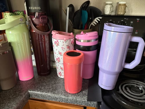 Customer's Thicc Buddy mugs in various colors and designs sitting on a kitchen counter.