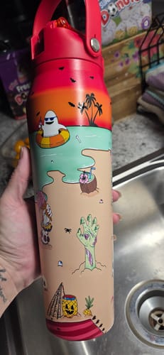 Reviewer holding a Bottle Buddy 32oz water bottle featuring a colorful tropical and Halloween-themed print.