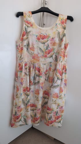 Customer's summer dress made from the floral Soft Blossoms linen look viscose fabric hanging on a hanger.
