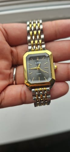 Customer's CLAIRE DE MAINS watch, a rectangular two-tone gold and silver timepiece held in a hand.