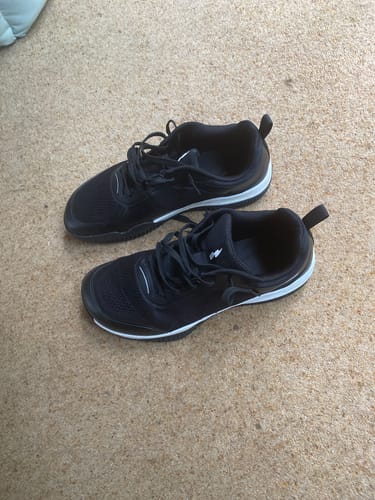 Customer's black CUURT Muuv wide toe box court shoes on a textured floor.
