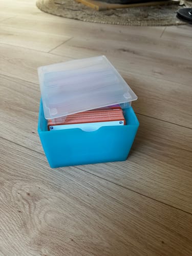 Customer's blue OXFORD FLASHBOX containing a stack of orange flashcards, set on a wooden floor.