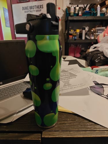 Customer's green and black lava patterned Bottle Buddy water bottle sitting on a desk.
