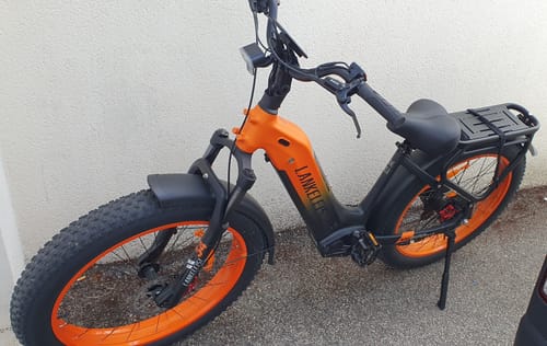 Customer's orange and black Lankeleisi MG600 Plus fat bike parked outside on a paved surface.