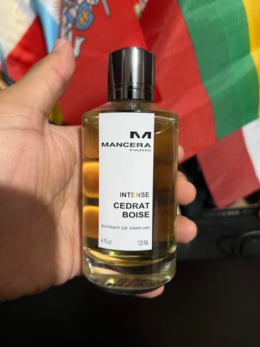 Customer's Mancera Cedrat Boise Intense perfume bottle held in hand in front of flags.