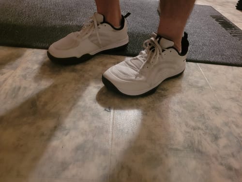 Customer's white CUURT Muuv court shoes with wide toe box being worn on a gym mat.