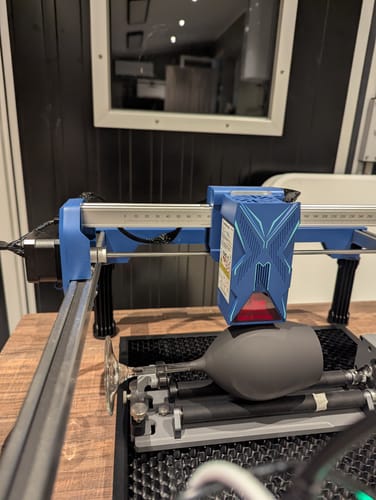 Customer's AtomStack Swift laser engraver set up with a rotating attachment engraving a wine glass