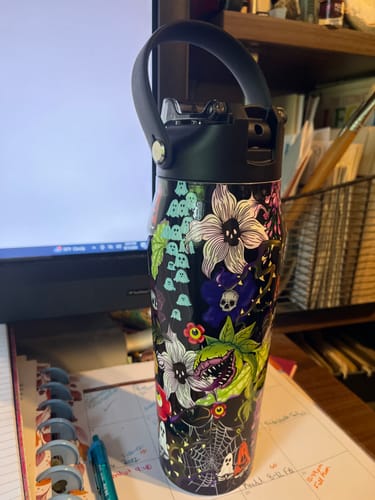 Customer's Toxic Bloom Bottle Buddy 24oz featuring a floral and ghost pattern on a desk.