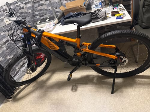 Customer's orange Lankeleisi MG600 Pro e-mountain bike parked in a room with a desk in the background.