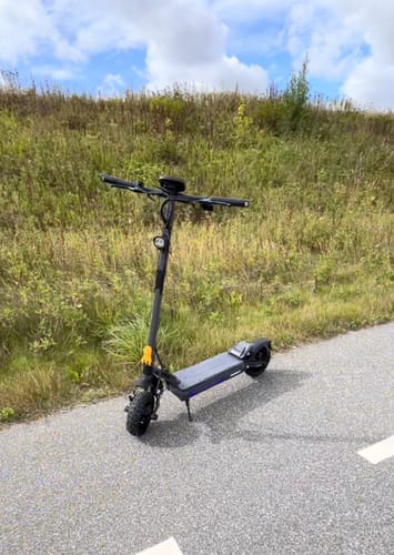 Customer's Ausom Gosoul 2 Electric Scooter parked on an asphalt path next to a grassy hill.