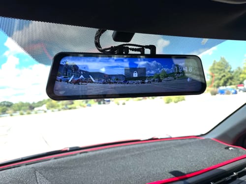 Customer's WOLFBOX G900TriPro dash cam mounted on a vehicle rearview mirror showing a digital road view.