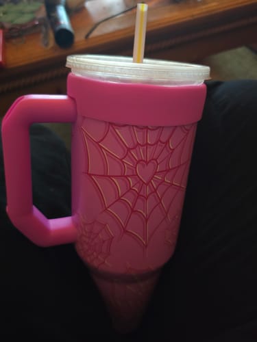 Customer's pink Thicc Buddy mug with spiderweb design, handle, and straw in a home setting.