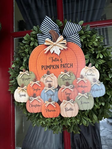 Customer's personalized Pumpkin Patch door hanger displayed on a green wreath on a door.