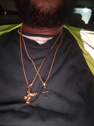 Customer's gold Franco chains worn around the neck, featuring hanging cross and angel pendants.