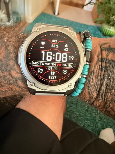 Customer's Gard Pro Ultra 3 watch with a circular digital display, worn on a tattooed wrist with a beaded bracelet.