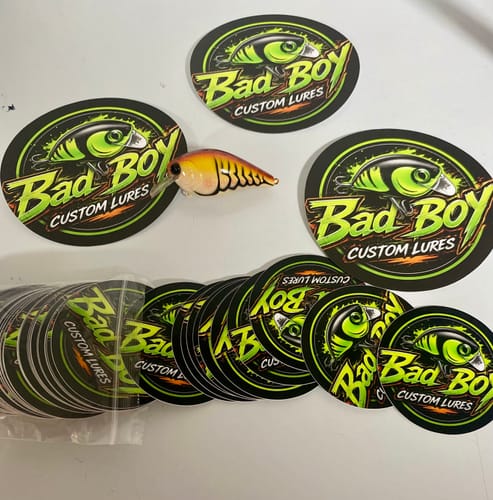 Customer's pile of round Bad Boy Custom Lures stickers with a colorful fishing lure placed on top.