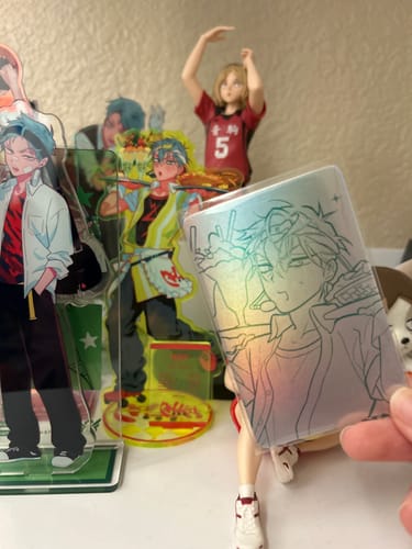 Reviewer's Alien Stage acrylic standee held in hand next to other displayed stands on a desk.