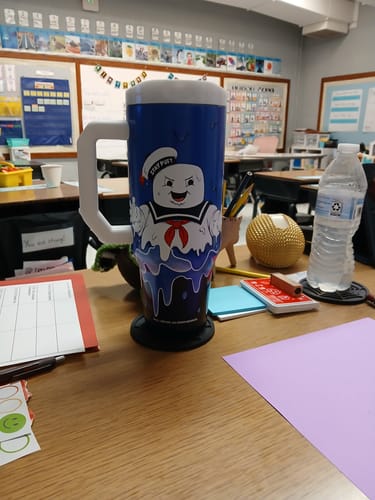 Reviewer's Ghostbusters Stay Puft Thicc Buddy cup sitting on a desk in a classroom setting