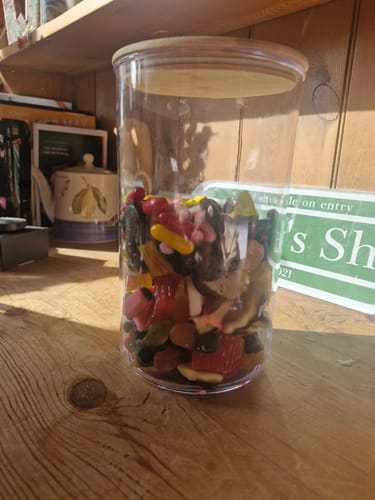 Customer's clear cylindrical jar filled with a variety of colorful Discovery Liquorice Bundle pieces on a wooden table.