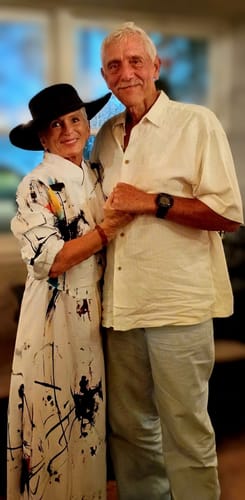 Customer's white shirt dress with black abstract print, worn with a black fedora while holding hands with another person.