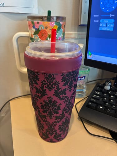 Customer's To-Go Buddy in black and deep pink patterned velvet design, holding a beverage with a red straw