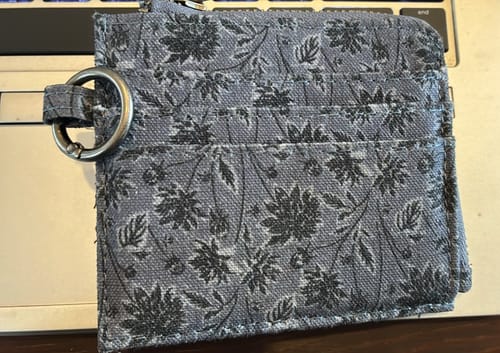 Customer's Tarjetero Canvas Flores Boho con diseño de flores, mostrando las ranuras para tarjetas y el llavero incluido.