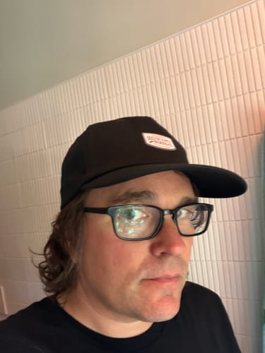 Customer's Big Relaxed Cap worn by a person, showing the black fabric and mid crown fit.