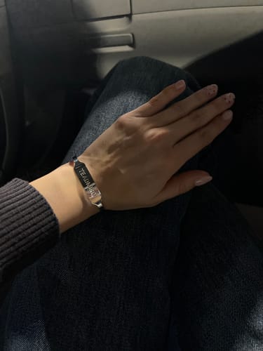 Customer's silver Esclava Abierta Placa Mensaje Woman bracelet worn on a person's wrist.