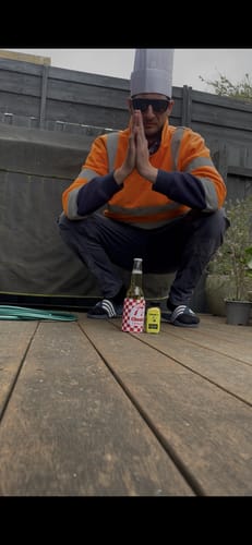 Reviewer's Chooki's Original Chicken Salt and another bottle resting on a deck in front of a person in chef attire.