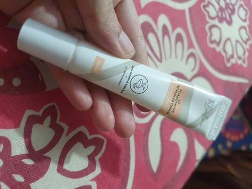 Customer's hand holding a tube of Advance Lip Pigmentation Cream with white and tan packaging.