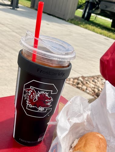 Customer's South Carolina Gamecocks To-Go Buddy tumbler with a red straw, sitting on a red surface outdoors.