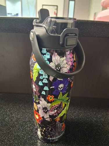 Reviewer's Bottle Buddy in Toxic Bloom pattern featuring spooky plants and spiderwebs, standing on a dark surface.