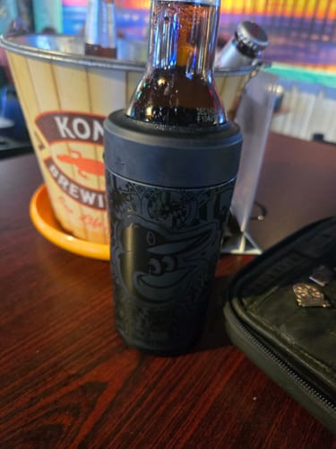 Customer's black Baltimore Orioles Universal Buddy cooler holding a glass bottle on a dark table.