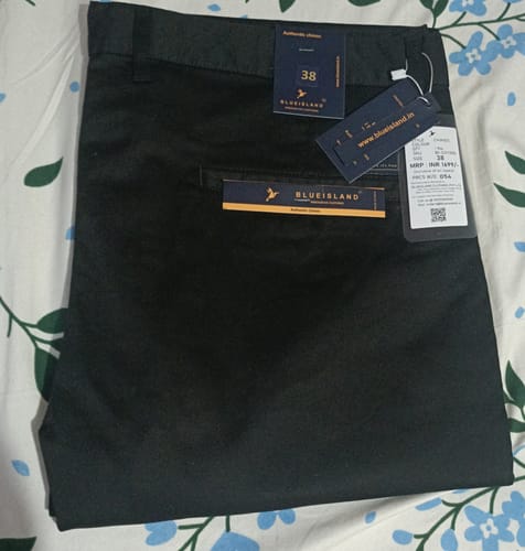 Customer's new black cotton pants with Blueisland brand tags attached, laid flat on floral bedding.