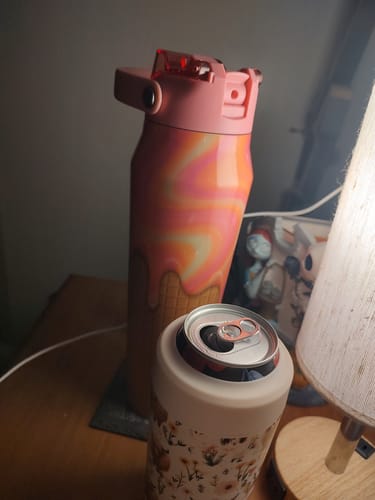 Customer's Sherbet Dripp Bottle Buddy standing on a table next to a floral can cooler.