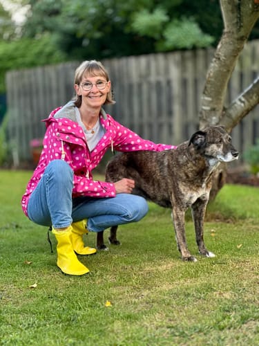 Customer's Brisk Ⅰ Barfuß-Gummistiefel in yellow worn while kneeling outdoors next to a dog.