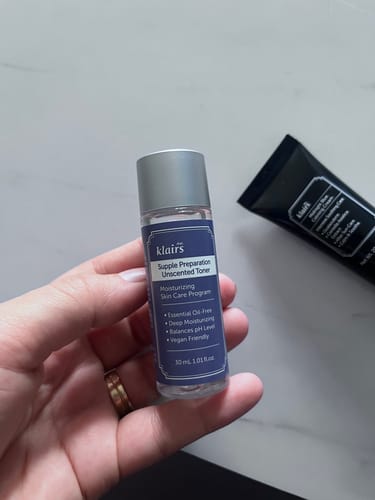 Customer's hand holding a small, clear bottle of Klairs Supple Preparation Unscented Toner.