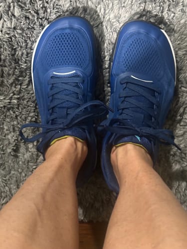 Customer's blue CUURT Muuv court shoes on a grey carpet.