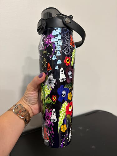 Reviewer's hand holding the Bottle Buddy 32oz Toxic Bloom water bottle with ghost and flower print.