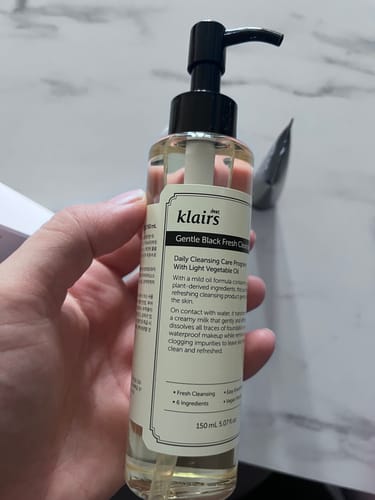Customer's hand holding the Gentle Black Fresh Cleansing Oil bottle with label details visible.