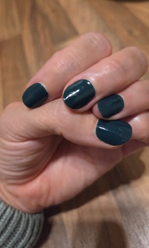 Customer's hand showing applied Evergreen Dream UV Gel Nail Wraps in a rich, dark green color.