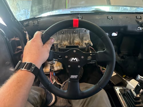 Reviewer's hand holding the installed black lightweight steering column in the interior of their S10 vehicle.