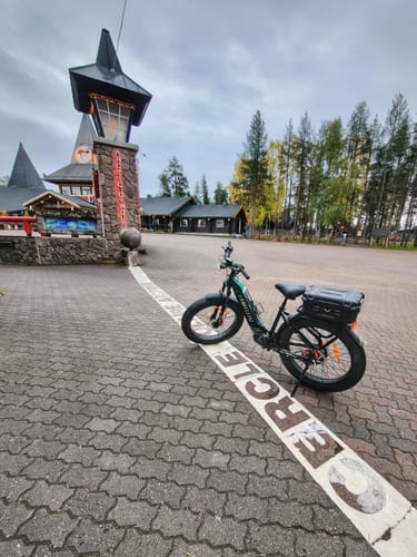 Customer's green Lankeleisi MG600 Plus e-bike parked on a paved path in front of a building in Santa Claus Village.