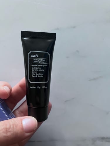 Customer's hand holding a small black tube of Klairs Midnight Blue Calming Cream