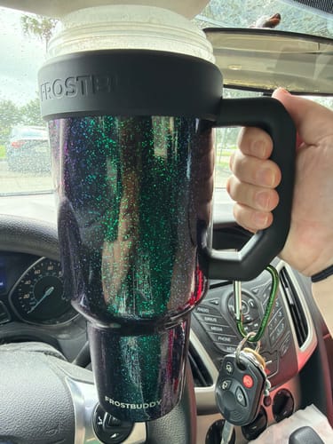 Reviewer's dark, sparkly Thicc Buddy mug held in a car, showing the keychain attached to the handle.
