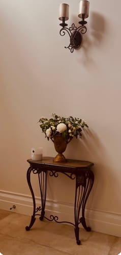 Customer's Bruno French Provincial Urn Planter holding a lush floral arrangement on an iron console table.