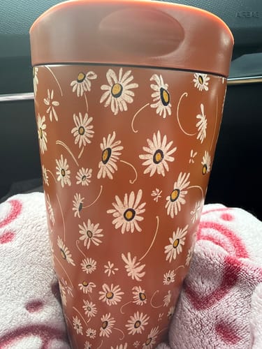 Customer's Sweet Daisy To-Go Buddy tumbler with a floral pattern, sitting on a soft surface.