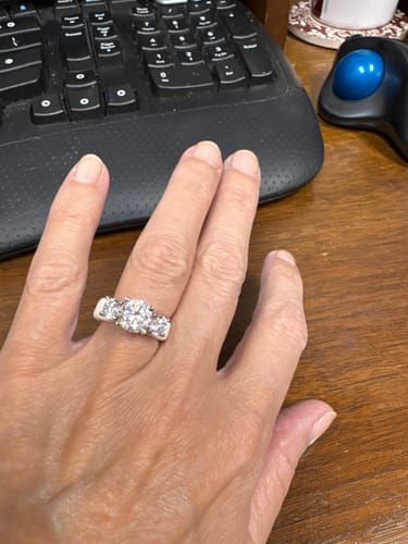 Reviewer's hand wearing a Rinfit silicone ring with three round stones while at a desk.