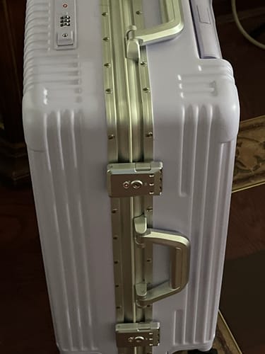 Customer's light purple hardshell luggage, showing a close-up of the metal locks, handle, and integrated combination lock.