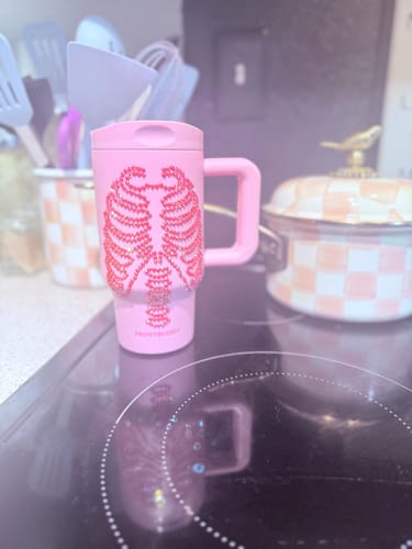 Customer's pink Mug Buddy with skeleton ribcage design sitting on a black stovetop.